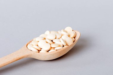 Renkli arka planda bir yığın beyaz hap. Tabletler masaya saçılmış. Kırmızı yumuşak jelatin kapsül yığını. Vitaminler ve beslenme takviyeleri konsepti.