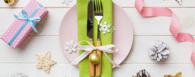 Noel süsleri, tabaklar, inekler, çatallar ve kaşıklarla Noel sofrası. Noel tatili geçmişi. Üst görünüm.