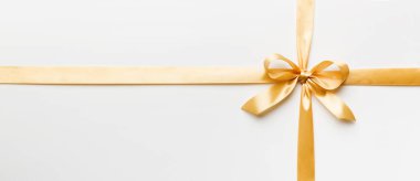 Altın kurdelenin üst görüntüsü yuvarlandı ve sarıyay renkli arka planda izole edildi. Kopyalama alanı olan düz.