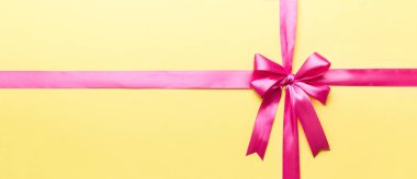 Mor kurdelenin üst görüntüsü yuvarlandı ve pembe fiyonk renkli arka planda izole edildi. Kopyalama alanı olan düz.