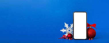 Digital phone mock up with rustic Christmas decorations for app presentation with empty space for you design. Christmas online shopping concept. Tablet with copy space on colored background.