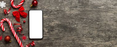 Digital phone mock up with rustic Christmas decorations for app presentation top view with empty space for you design. Christmas online shopping concept. Tablet with copy space on colored background.
