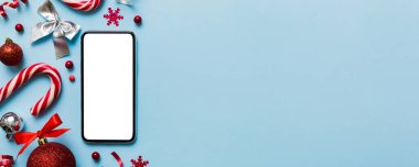 Digital phone mock up with rustic Christmas decorations for app presentation top view with empty space for you design. Christmas online shopping concept. Tablet with copy space on colored background.