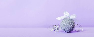 Christmas ball on colored background. decoration bauble with ribbon bow with copy space.