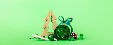 Christmas ball with decorative wooden tree on colored background. decoration bauble with ribbon bow with copy space.