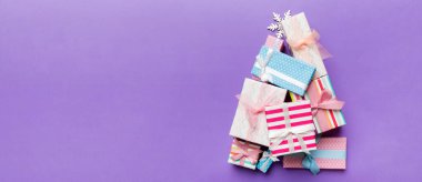 Renkli arka planda güzel paketlenmiş hediyelerden yapılmış Noel ağacı, yukarıdan görünüyor. Kopya alanı olan en küçük hediye kutusu konsepti.