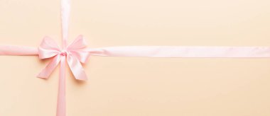 Mor kurdelenin üst görüntüsü yuvarlandı ve pembe fiyonk renkli arka planda izole edildi. Kopyalama alanı olan düz.