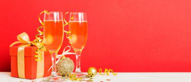 Champagne glasses and christmas decor on colored holiday background. Flat lay New Year decorations.