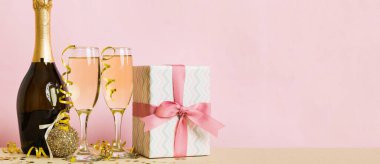 Champagne bottle with confetti, glasses and christmas decor on colored holiday background. Flat lay New Year decorations.