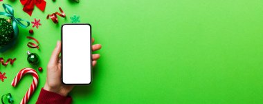 Mesaj atmak için yeri olan bir Noel modeli. Noel reklamı, uygulama şablonu. Masa arkasında boş ekran olan el ele tutuşan telefon. Mutlu yıllar ve Xmas Flat.