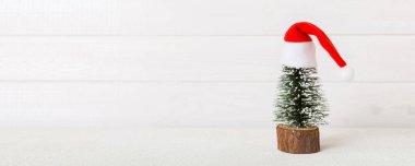 One small Christmas tree with santa hat on colored background. new year decoration with copy space.