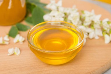 Tatlı bal kavanozu bahar akasyası çiçeklerini sarmıştı. Kavanozdaki kaşıktan bal akar. Tahta zemin üzerinde taze akasya balı kavanozları.