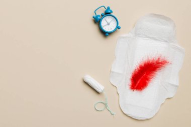 Alarm saatini hijyenik kadın tamponları ve regl pedleri ile çalıyor. Tıbbi konsept kadın kritik günler ve regl dönemi. Kadın günlük hijyen. Boşluğu kopyala.