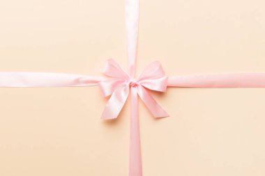 Mor kurdelenin üst görüntüsü yuvarlandı ve pembe fiyonk renkli arka planda izole edildi. Kopyalama alanı olan düz.