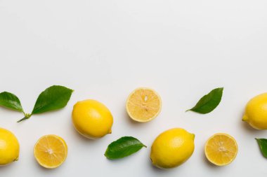 Renkli arka planda yeşil yapraklı taze limonlar, üst görünüm, metin için boşluk.