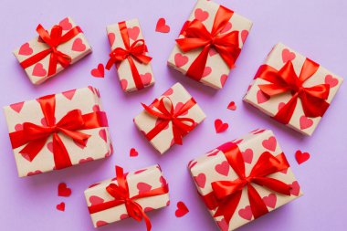 Top view photo of valentine day decorations gift box with red ribbon bow on colored background. Holiday gift boxes with top view.