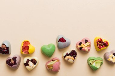 chocolate sweets in the form of a heart with fruits and nuts on a colored background. top view with space for text, holiday concept.