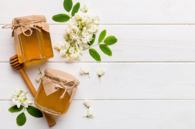 Akasya çiçekli ve yapraklı bal kavanozu. Taze bal üst görünüm düz yatıyordu.