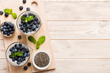 Sağlıklı kahvaltı ve chia tohumlu vanilyalı puding ve böğürtlenli masa arkası, vejetaryen gıda, diyet ve sağlık konsepti. Hindistan cevizi sütü ve yabanmersinli Chia pudingi..