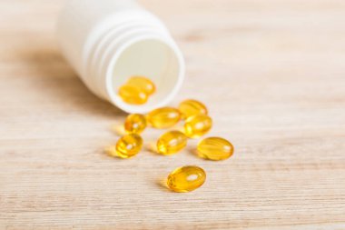 Soft gels pills with Omega-3 oil spilling out of pill bottle close-up. Gel capsules bottle white surface. Omega 3, multivitamins, Calcium, antibiotics. Health. Immunity.