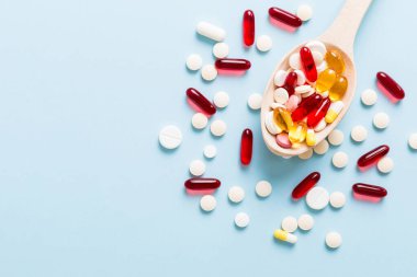 Renkli bir arka planda kaşıkta vitamin kapsülleri. Haplar sağlıklı bir yemek olarak sunuldu. Kırmızı yumuşak jel vitamin takviye kapsülleri kaşık üzerinde.