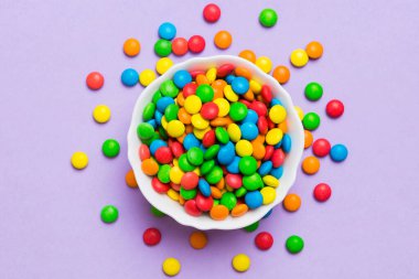 Renkli arka planda bir kasede çok renkli şekerler. Doğum günü ve tatil konsepti. Kopyalama alanı olan üst görünüm.