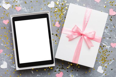 Gift box of open tablet for the holidays with a bow top view.
