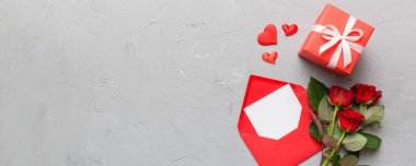 Zarflı sevgililer günü kompozisyonu, gül çiçeği ve kırmızı kalp masada. Üst manzara, düz yatış. Tatil kavramı.