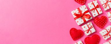 Hediye kutularının ve renkli arka planda kırmızı tekstil kalplerinin üst görüntüsü. Kopya alanı ile Sevgililer Günü konsepti.