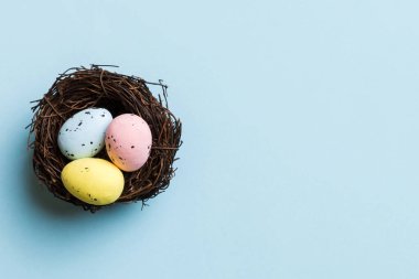 Colorful easter eggs in nest on table background with copy space top view.