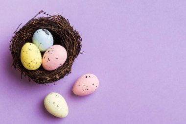 Colorful easter eggs in nest on table background with copy space top view.