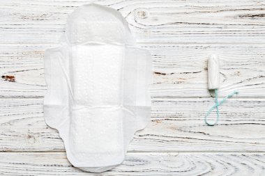 Kadın pedleri ve tamponları. Pembe ve menekşe arka planda izole edilmiş bir arka planda hijyenik pedlerin yanında uzanıyor. Kadın hijyeni ve adet dönemi konsepti.