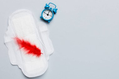 Alarm saatini hijyenik kadın tamponları ve regl pedleri ile çalıyor. Tıbbi konsept kadın kritik günler ve regl dönemi. Kadın günlük hijyen. Boşluğu kopyala.