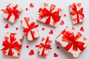 Top view photo of valentine day decorations gift box with red ribbon bow on colored background. Holiday gift boxes with top view.