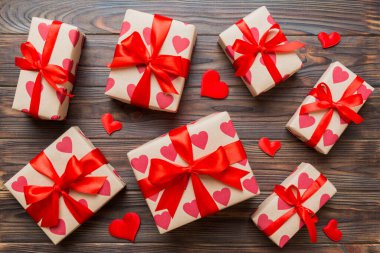 Top view photo of valentine day decorations gift box with red ribbon bow on colored background. Holiday gift boxes with top view.