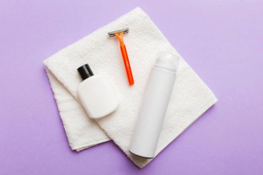 Tıraş Adam seti. Traş makinesi, havlu, losyon ve renkli arka planda tıraş köpüğü. Erkekler banyo aksesuarları üst görünüm.