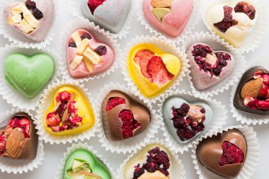 chocolate sweets in the form of a heart with fruits and nuts on a colored background. top view with space for text, holiday concept.