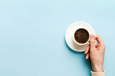 Renkli arka planda bir fincan kahve tutan minimalist stil bir kadın. Düz yatıyordu, üstten espresso fincanı. Metin için boş yer, kopyalama alanı. Kahve bağımlılığı. Üst manzara, düz uzanma.