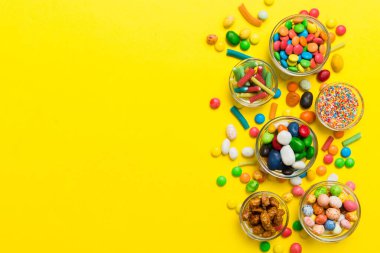 farklı renkte yuvarlak şekerler ve kavanozlar. Fotokopi alanı olan büyük çeşitlilikteki şeker ve şekerlerin üst görünümü.