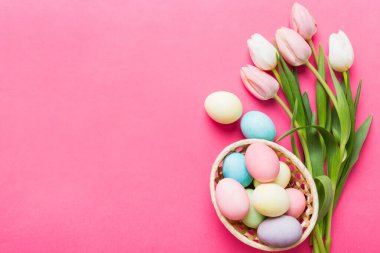 Mutlu Paskalya kompozisyonu. Renkli masada sarı laleli sepetli Paskalya yumurtaları. Doğal boyalı renkli yumurtalar arkaplan arkaplan görünümü kopya alanı ile.