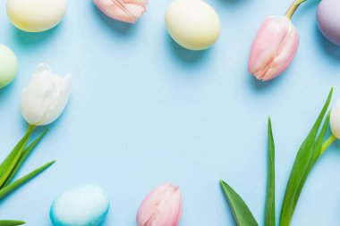 Mutlu Paskalya kompozisyonu. Renkli masada sarı laleli Paskalya yumurtaları. Doğal boyalı renkli yumurtalar arkaplan arkaplan görünümü kopya alanı ile.