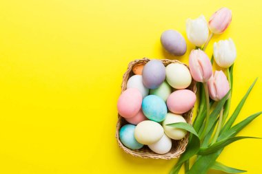 Mutlu Paskalya kompozisyonu. Renkli masada sarı laleli sepetli Paskalya yumurtaları. Doğal boyalı renkli yumurtalar arkaplan arkaplan görünümü kopya alanı ile.