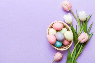 Mutlu Paskalya kompozisyonu. Renkli masada sarı laleli sepetli Paskalya yumurtaları. Doğal boyalı renkli yumurtalar arkaplan arkaplan görünümü kopya alanı ile.
