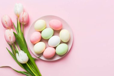 Mutlu Paskalya kompozisyonu. Renkli masada sarı laleli sepetli Paskalya yumurtaları. Doğal boyalı renkli yumurtalar arkaplan arkaplan görünümü kopya alanı ile.