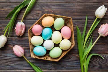 Mutlu Paskalya kompozisyonu. Renkli masada sarı laleli sepetli Paskalya yumurtaları. Doğal boyalı renkli yumurtalar arkaplan arkaplan görünümü kopya alanı ile.
