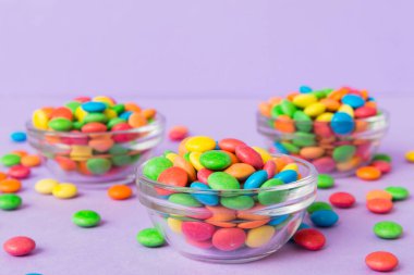 Renkli arka planda bir kasede çok renkli şekerler. Doğum günü ve tatil konsepti. Kopyalama alanı olan üst görünüm.