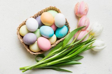 Mutlu Paskalya kompozisyonu. Renkli masada sarı laleli sepetli Paskalya yumurtaları. Doğal boyalı renkli yumurtalar arkaplan arkaplan görünümü kopya alanı ile.