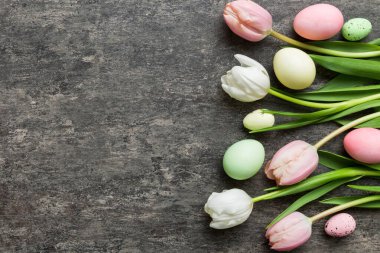 Mutlu Paskalya kompozisyonu. Renkli masada sarı laleli Paskalya yumurtaları. Doğal boyalı renkli yumurtalar arkaplan arkaplan görünümü kopya alanı ile.