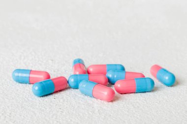 Renkli arka planda bir yığın pembe ve mavi hap. Tabletler masaya saçılmış. Kırmızı yumuşak jelatin kapsül yığını. Vitaminler ve beslenme takviyeleri konsepti.