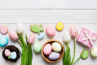 Yumurtalı Paskalya çerçevesi, renkli bir arka planda hediye kutusu ve lale. Minimum konsept. Üst Manzara Mutlu Paskalyalar kompozisyonu. Metin için yerin bir kopyasına sahip kart.